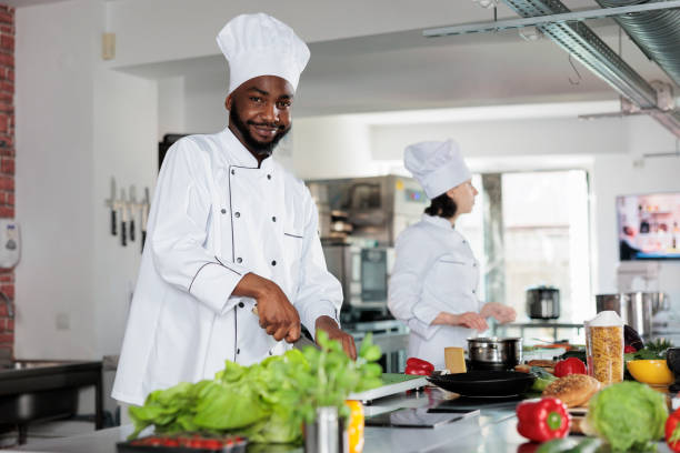 istock Confident head chef in restaurant professional kitchen, cutting vegetables and preparing garnish for dinner dish recipe. 1446919338
