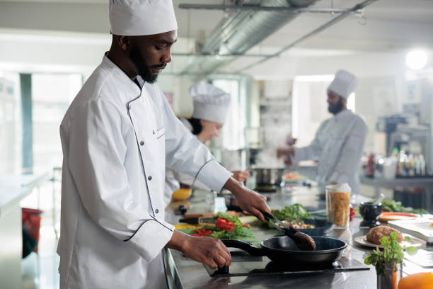 istock African american head cook searing succulent beef patty while preparing food for dinner service at restaurant. 1446919762