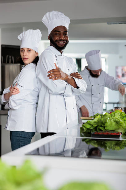 istock Multiethnic gastronomy experts standing in restaurant kitchen with arms crossed while posing at camera. 1446919901