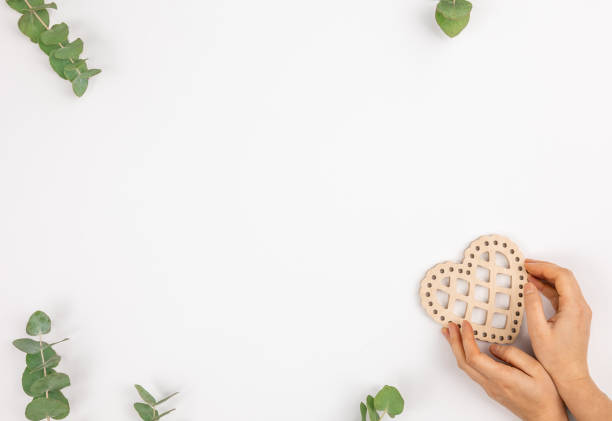 fundo branco minimalista com um coração de madeira nas mãos femininas, flat lay. - heart shape isolated isolated on white tea leaves - fotografias e filmes do acervo