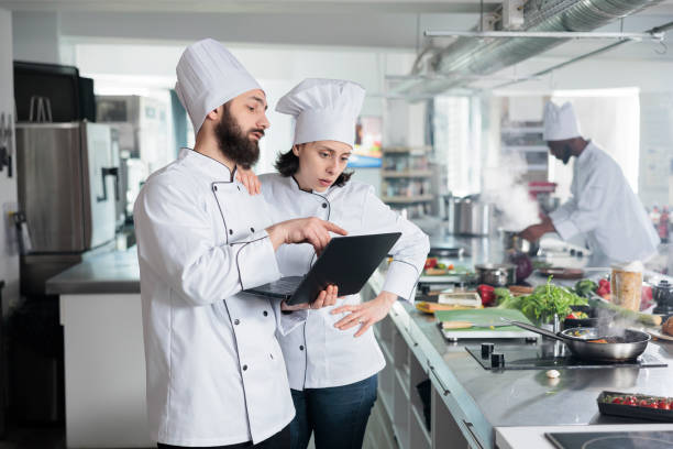 istock Sous chef with modern laptop recommending dinner dish service recipe to head chef 1446920395