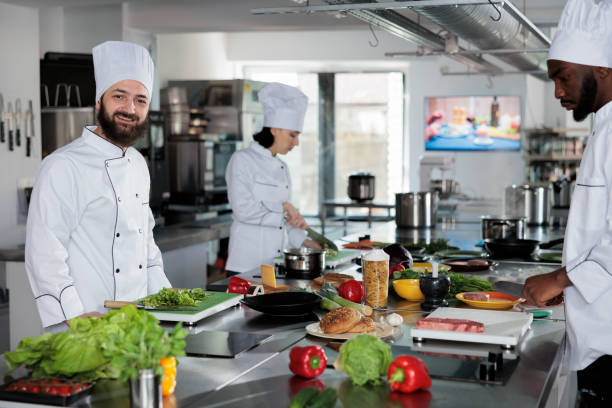 istock Positive smiling head chef in restaurant professional kitchen space preparing gourmet meal using delicious ingredients. 1446921364