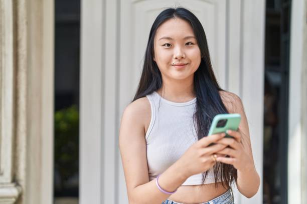istock Young chinese woman smiling confident using smartphone at street 1446921514