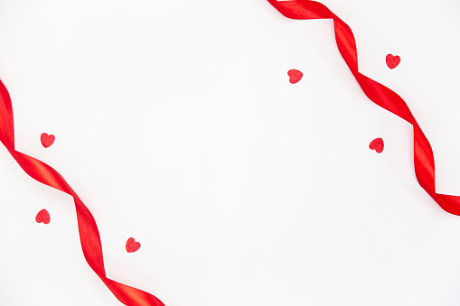 Red ribbons and decorative hearts on a white background isolated, flat lay, copy space.