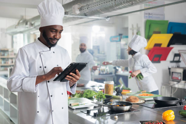 istock Gastronomy expert with handheld device standing in restaurant professional kitchen while looking for dinner recipes. 1446921953