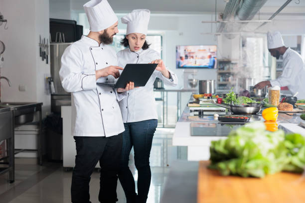 istock Gastronomy experts using computer to decide what ingredients to use for gastronomic event held at restaurant. 1446922451