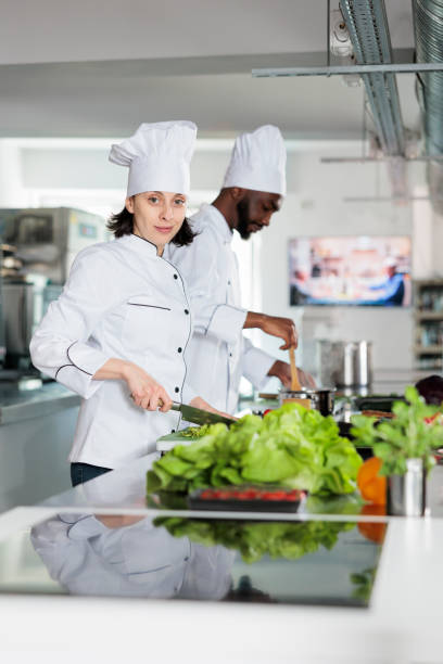 istock Caucasian woman chef cutting fresh herbs and preparing ingredients for delicious dish while looking at camera. 1446922775