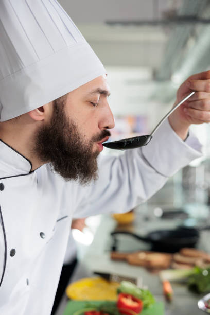 istock Head chef tasting delicious gourmet dish cooked in professional kitchen and served at dinner service in fine dining restaurant. 1446923396