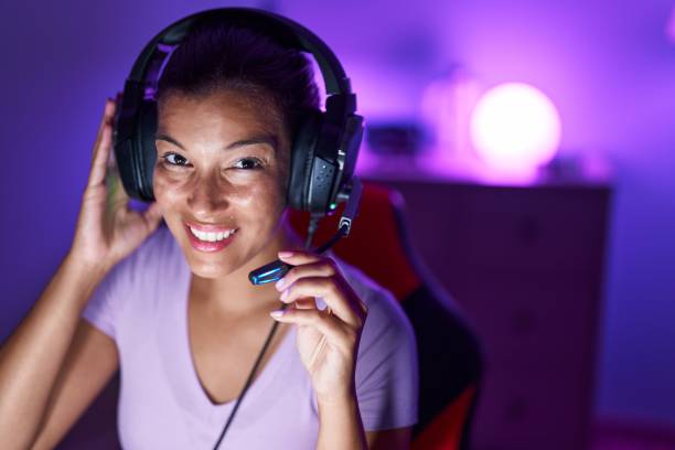 istock Young beautiful hispanic woman streamer playing video game using computer at gaming room 1446923499