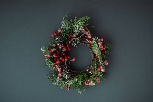 istock Christmas background with festive wreath decorated with red berries and cone on grey background. Flat lay. Copy space for a greeting text 1446923715