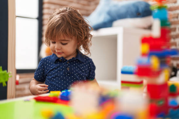istock Adorable hispanic toddler playing with construction blocks standing at kindergarten 1446923902