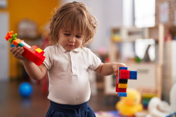 istock Adorable hispanic toddler playing with construction blocks standing at kindergarten 1446924021