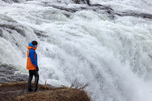 man in winter coat looking at the Faxi (Vatnsleysufoss) waterfall on the Tungufljót river