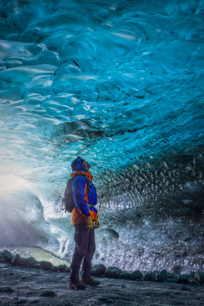 man standing in a beautiful blue ice cave of the Vatnajökull glacier in Iceland stock photo
