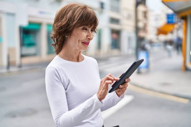 istock Middle age woman smiling confident using touchpad at street 1446925861