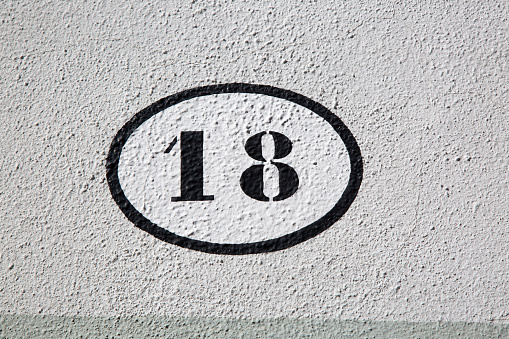 Close-up of Black and White Number Eighteen on Stone Wall