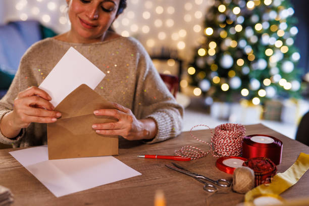 istock Woman putting a Christmas letter, that she wrote, in a gold colored envelope 1446926391