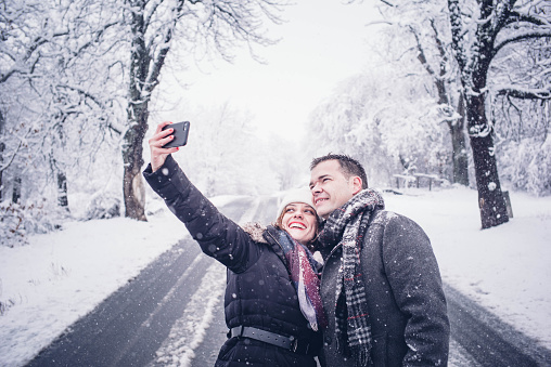 Couple man and woman make selfie in snow.