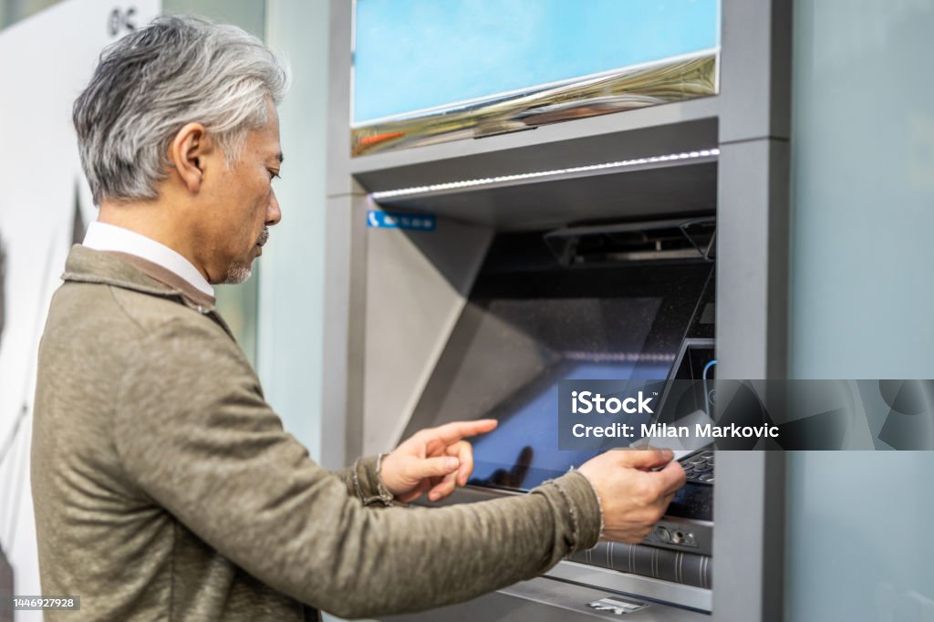 There is something wrong with my bank card A mature man, a Japanese man, uses an ATM to withdraw his money faster and without waiting in the bank, but he encounters a big problem with his bank card. ATM Stock Photo