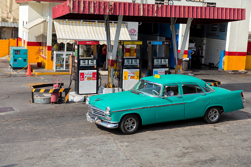 Havana, Cuba - April 20, 2018: Vintage American car refuels at a gasoline station in Havana on a sunny day.