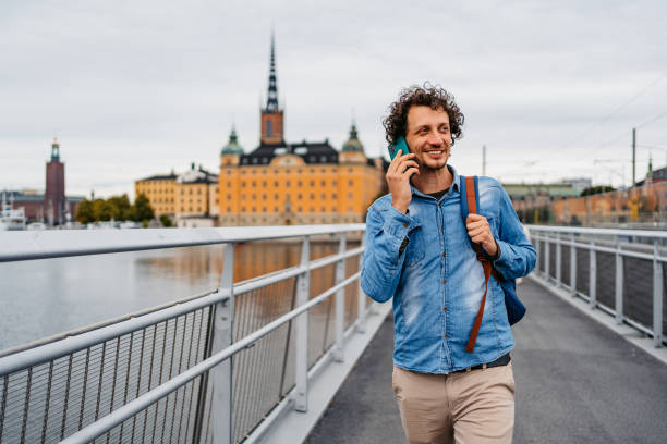 istock Young Man Talking On The Phone While Walking On The Bridge In Stockholm 1446931016
