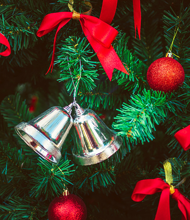 Twin silver bells and red ribbon with red Christmas balls adorn on Christmas tree.  Christmas background. New Year concept.