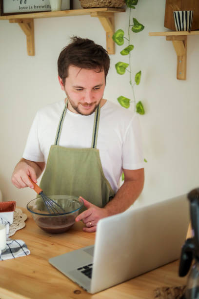 istock Young Man Making Cake With Recipe , Man In The Kitchen 1446932419