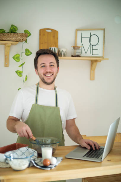 istock Young Man Making Cake With Recipe , Man In The Kitchen 1446933038