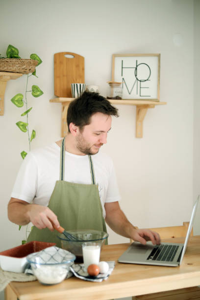 istock Young Man Making Cake With Recipe , Man In The Kitchen 1446933054