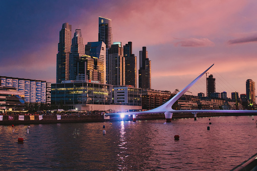 Cityscape of Puerto Madero buildings, bridge and river at sunset, Buenos Airest. Taken on a warm afternoon under a colorful sunset sky