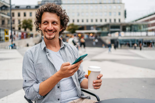 istock Young Man Using Phone And Drinking Coffee In Stockholm 1446935121
