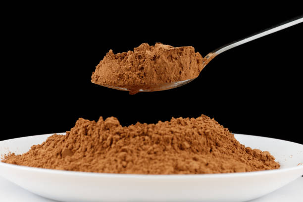 istock Cocoa powder on a spoon on black close-up 1446935338