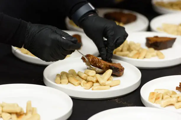 Photo of chef is serving pasticada with gnocchi, beef stew in a sauce. Croatian cuisine