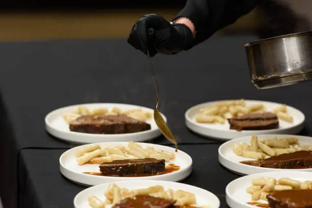 Photo of chef is serving pasticada with gnocchi, beef stew in a sauce. Croatian cuisine