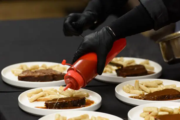 Photo of chef is serving pasticada with gnocchi, beef stew in a sauce. Croatian cuisine