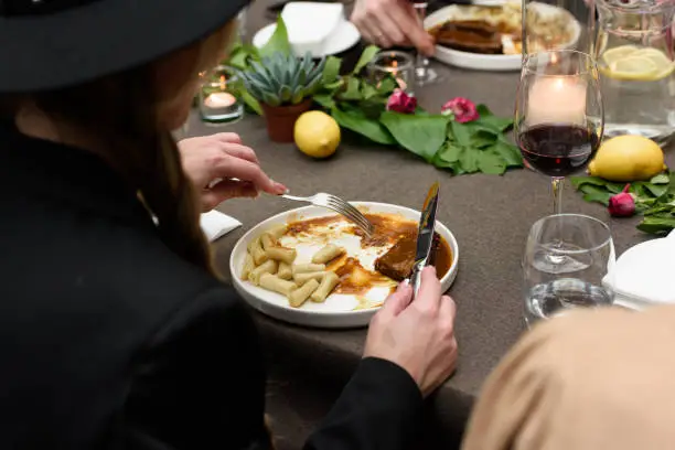 Photo of Woman eating pasticada with gnocchi, beef stew in a sauce. Croatian cuisine