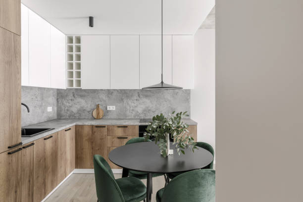 istock Modern minimalistic kitchen and dining room interior with wooden and white surfaces, green chairs and eucalyptus in ceramic vase. Aesthetic simple interior design concept. 1446937253