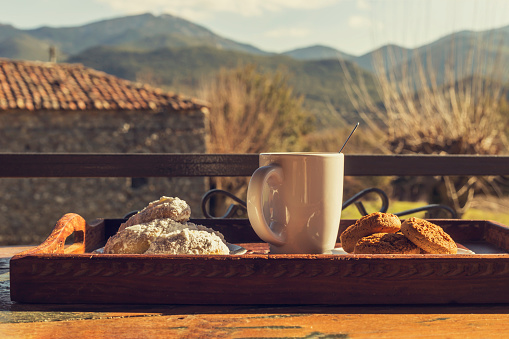 New Year and Christmas composition. National, Christmas greek cookies melomacarona, kourabies and a cup of coffee close-up against the background of the village and mountains