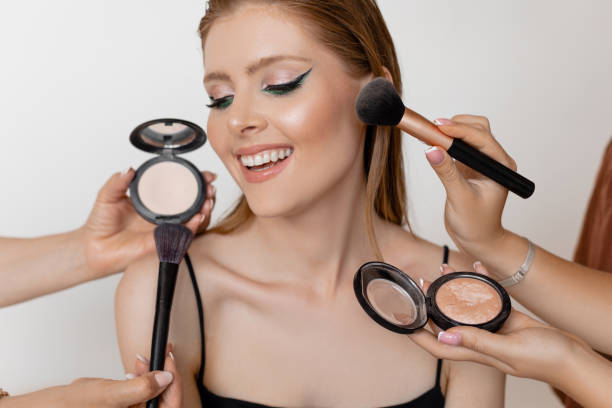 istock Young cheerful woman with make-up looking aside on white background with brushes, face powder, rouge holded by hands. 1446940603