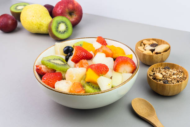 istock Fresh fruit salad in a bowl. Multicolored and tropical fruits. Pineapple, mango, grape, strawberry, papaya, melon, kiwi. Additional with chestnuts and granola. Selective focus 1446943210