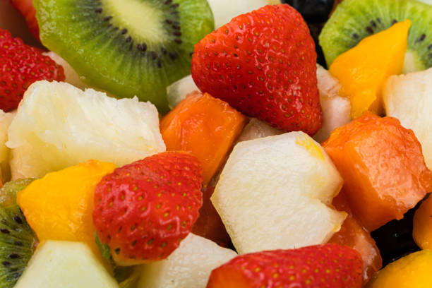 istock Fresh fruit salad in a bowl. Multicolored and tropical fruits. Pineapple, mango, grape, strawberry, papaya, melon, kiwi. Additional with chestnuts and granola. Selective focus 1446943877
