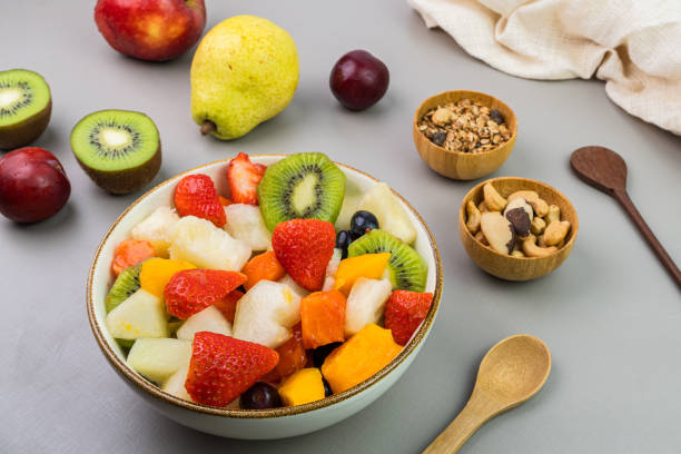 istock Fresh fruit salad in a bowl. Multicolored and tropical fruits. Pineapple, mango, grape, strawberry, papaya, melon, kiwi. Additional with chestnuts and granola. Selective focus 1446943953