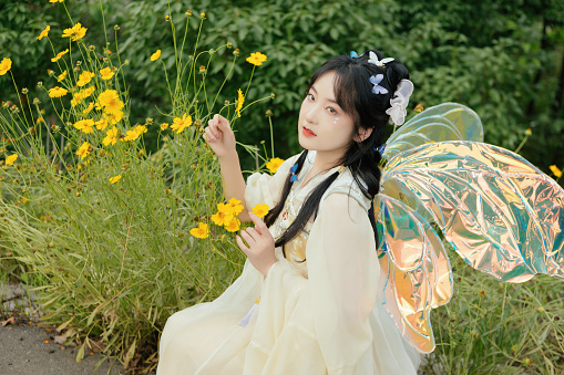 Two little fairies embrace, one in a pink shirt, the other in the blue shirt, both with pink wings, crown and magic wands against dark background