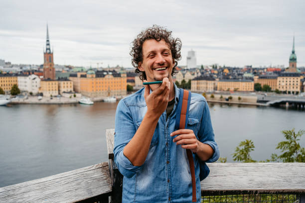 young man sending a voice message at a high viewpoint in stockholm - vocoder imagens e fotografias de stock