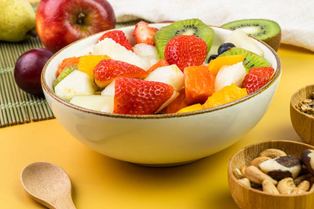 istock Fresh fruit salad in a bowl. Multicolored and tropical fruits. Pineapple, mango, grape, strawberry, papaya, melon, kiwi. Additional with chestnuts and granola. Selective focus 1446944751