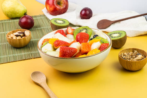 istock Fresh fruit salad in a bowl. Multicolored and tropical fruits. Pineapple, mango, grape, strawberry, papaya, melon, kiwi. Additional with chestnuts and granola. Selective focus 1446944807