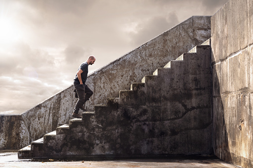 A man in casual clothing is walking up stairs made out of concrete.