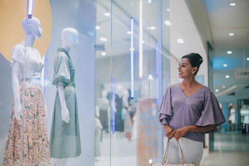 Asian Indian Woman window shopping looking at womenswear at shopping mall