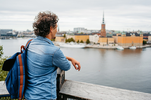 Handsome young man looking at the view of old own Stockholm from the high viewpoint.