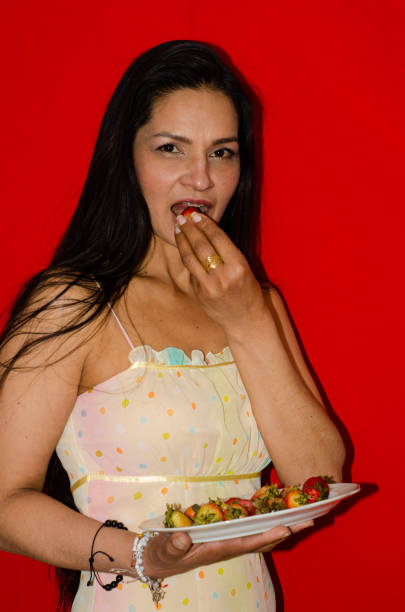 istock Woman eating strawberries with colored background 1446945528